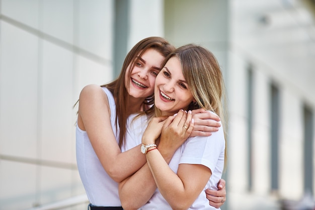 La hija adulta abraza a la madre y ambas están sonriendo a la cámara.