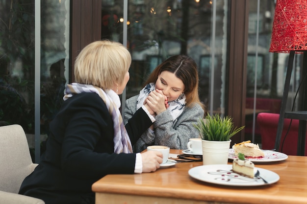 Hija adulta besa la mano de su madre y sonríe