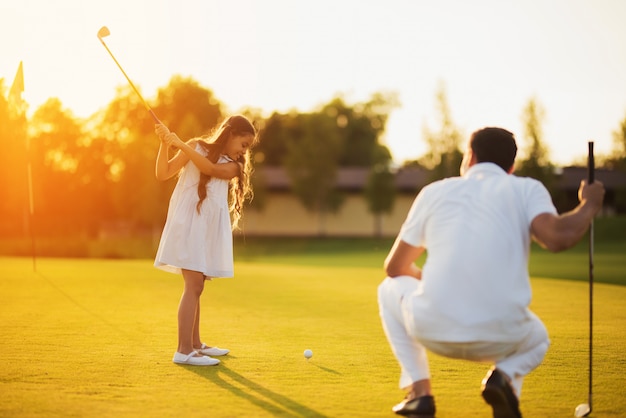 La hija aprende a tomar la familia feliz del tiro de golf.