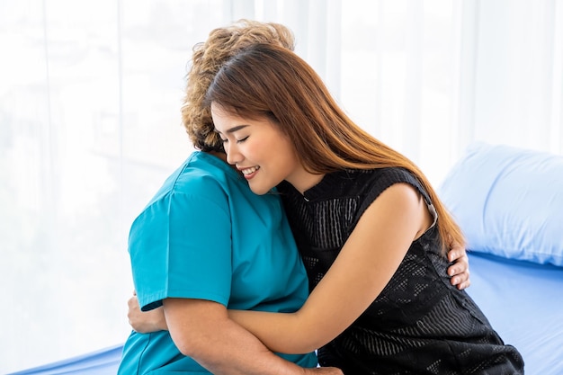 Una hija asiática joven visita a una anciana madre paciente en el hospital para apoyar y motivar el concepto médico y de atención médica