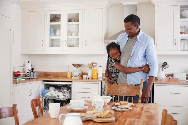 Hija ayudando a padre a despejar la mesa después de la comida familiar