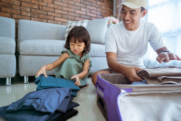 Hija ayudando a su papá a poner ropa en la maleta