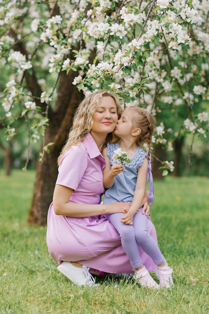 Hija besa a mamá en la mejilla en el parque de primavera