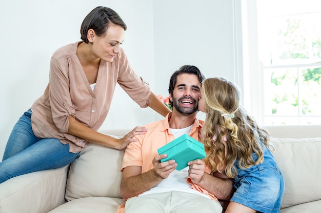 Hija besando a padre mientras madre sentada junto a ellos