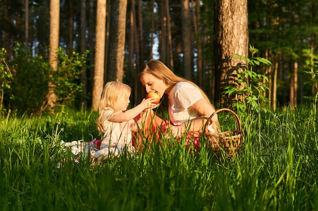 Hija comparte manzana con su mamá durante un picnic en el parque