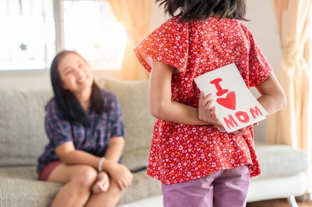 La hija da la tarjeta de felicitación del día de la madre a la mamá