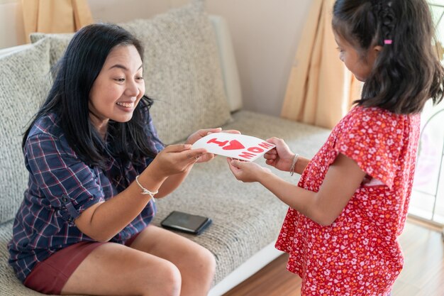 La hija da la tarjeta de felicitación del día de la madre a la mamá