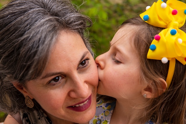 Hija dando un beso en la mejilla a su madre