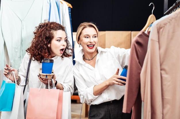 Hija emocional. Hija rizada se siente emocional al ver un suéter con estilo increíble en la tienda