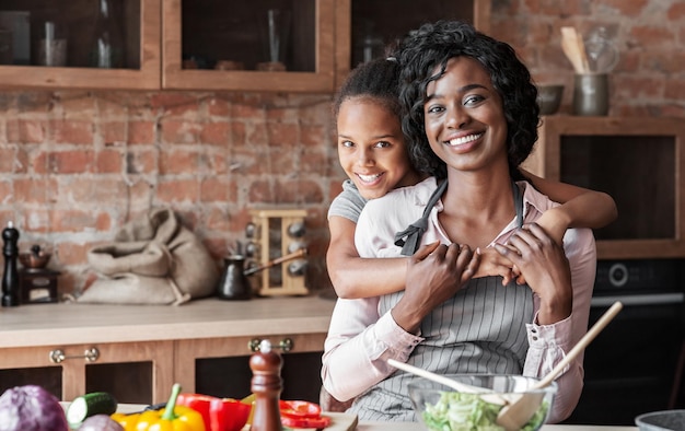 Una hija encantadora abrazando a su madre con amor en la cocina.