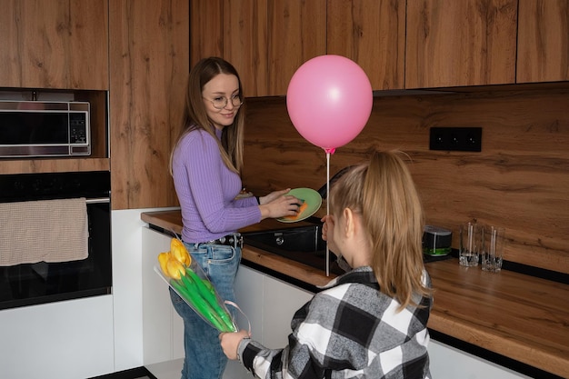 La hija felicita a su madre por el Día de la Madre le regala un globo y flores