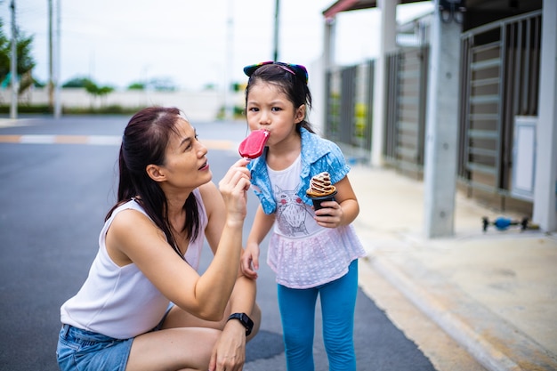 Hija feliz jugando y comiendo helado con la madre al aire libre