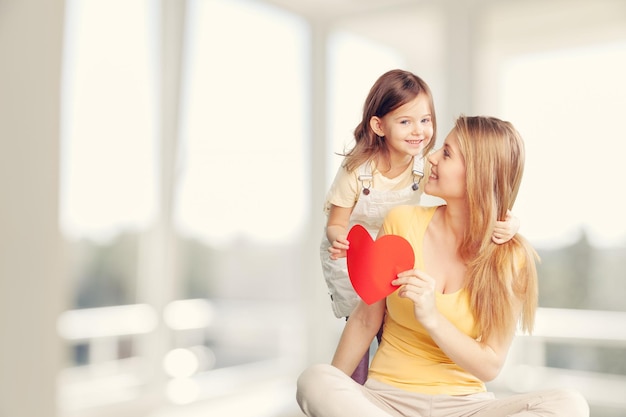 La hija feliz del niño da un corazón para la madre