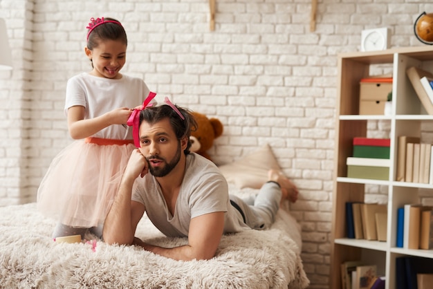 Hija haciendo peinados a su padre en el dormitorio