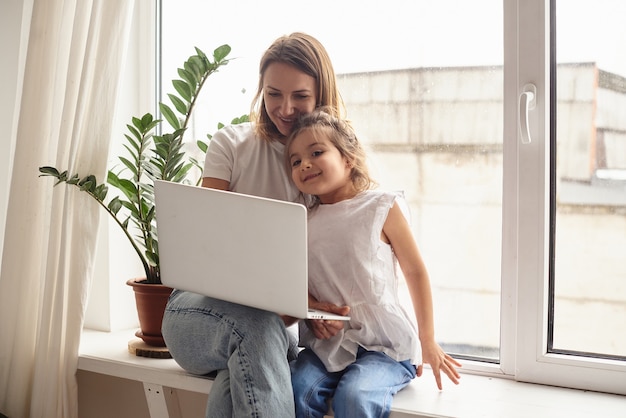 Hija juega con mamá y gato mientras mamá trabaja en la computadora