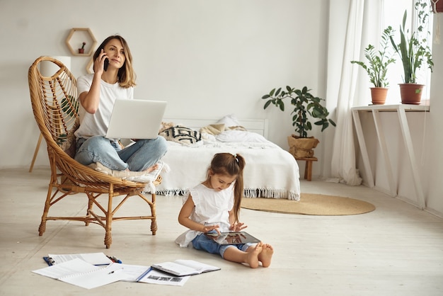 Hija juega con mamá y gato mientras mamá trabaja en la computadora