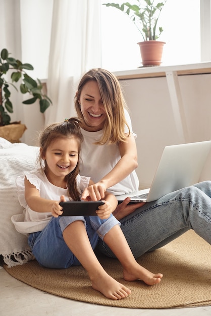 Hija juega con mamá y gato mientras mamá trabaja en la computadora