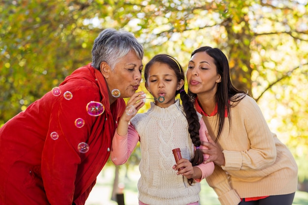 Hija con madre y abuela soplando burbujas