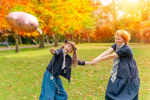 Hija y madre divirtiéndose en el parque de otoño