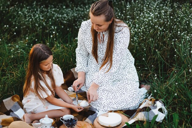 Una hija y una madre hacen un picnic en el jardín.
