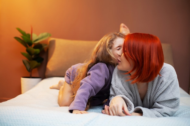 Hija y madre jugando en la cama en la guardería