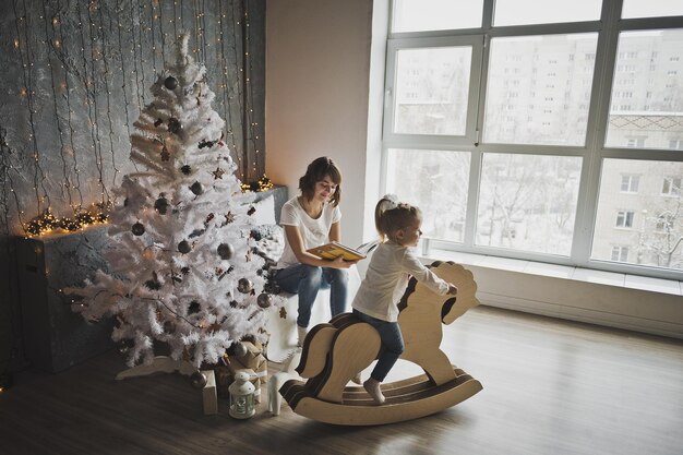 Hija con madre jugar alrededor del árbol de navidad 7087