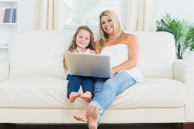 Hija y madre que se relajan en el sofá con el cuaderno