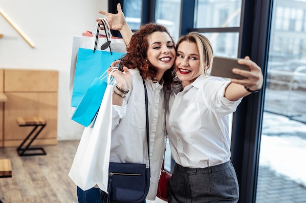 Hija mayor. Hermosa mujer rubia haciendo fotos con su hija mayor después de la hora de compras