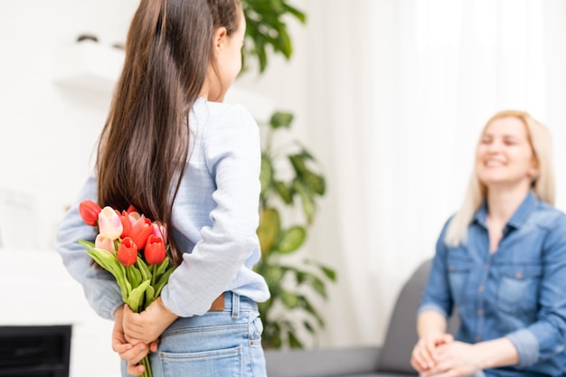 la hija del niño felicita a la madre y le da un ramo de tulipanes de flores.