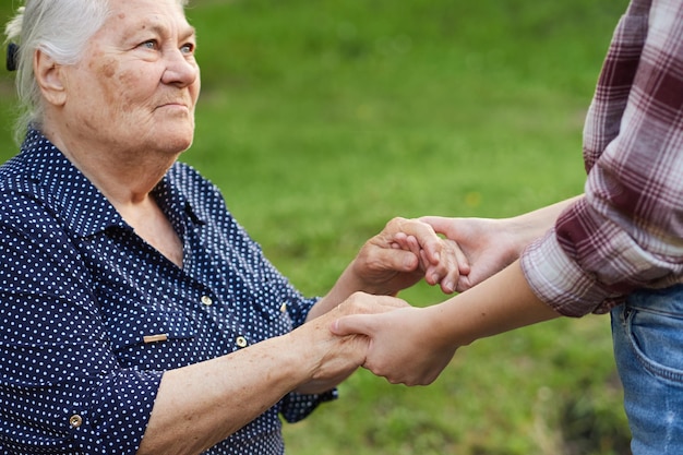 Hija o nieta sostiene las manos de una anciana que la ayuda a levantarse