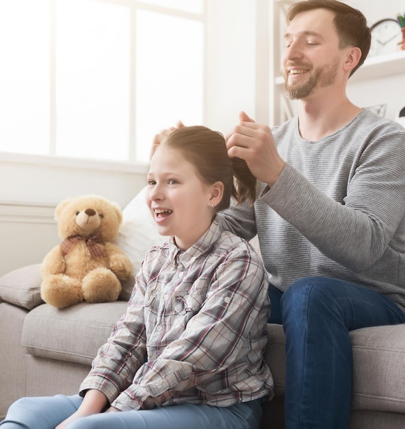 Hija de padre guapo peinado mientras pasan tiempo juntos en casa