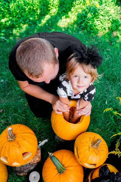 Foto la hija y el padre sacan semillas y material fibroso de una calabaza antes de tallarla para halloween. prepara un jack-o-lantern. decoración para fiesta. familia feliz. pequeño ayudante. vista superior.