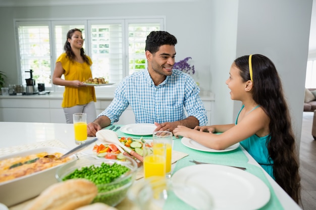 Hija y padres comiendo en la mesa en casa