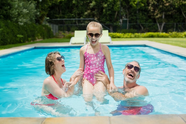 Foto hija y padres felices divirtiéndose en la piscina