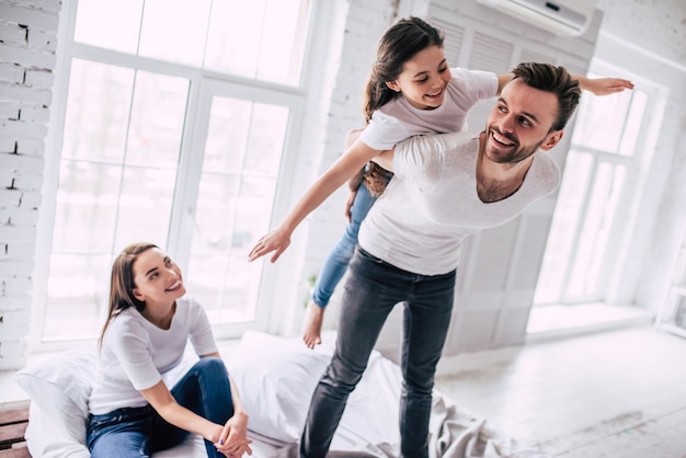 La hija con los padres jugando en la cama.