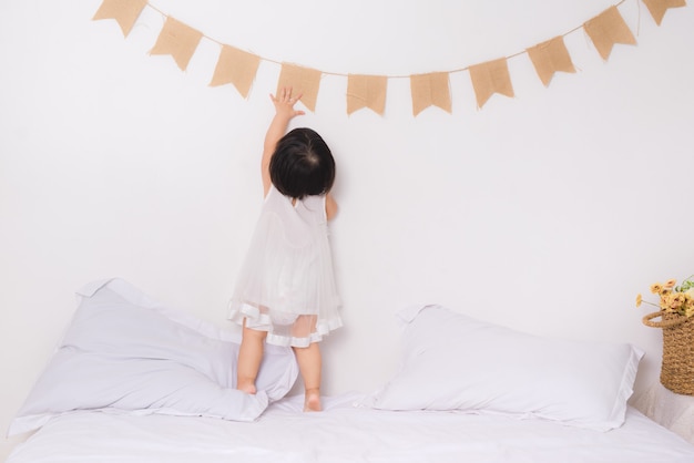 Hija princesa encantadora sentada en la cama en casa.