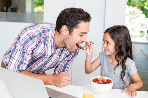 Hija sonriente que alimenta la comida al padre