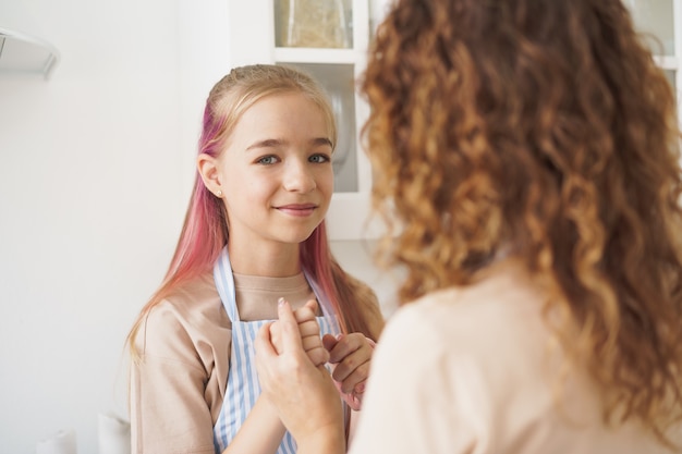 Hija sonriente y su madre de pie y tomados de la mano mirando el uno al otro