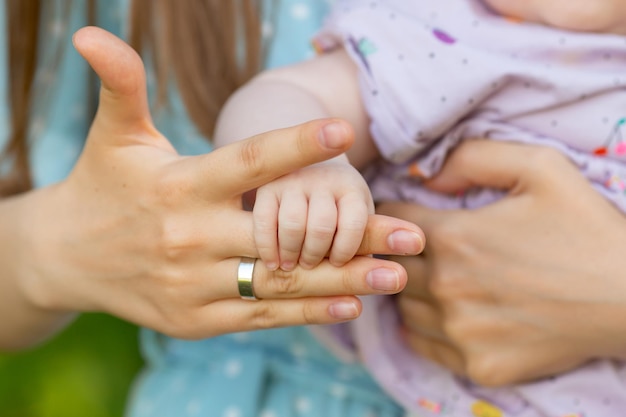 La hija sostiene el dedo de su madre en la naturaleza.