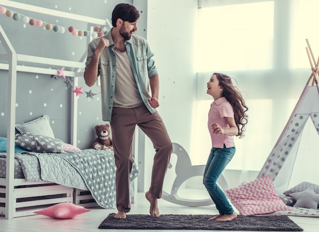 Hija y su guapo papá están bailando y sonriendo.