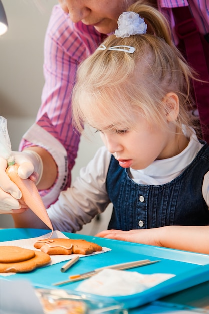 Hija y su madre decorando pan de jengibre con azúcar glas