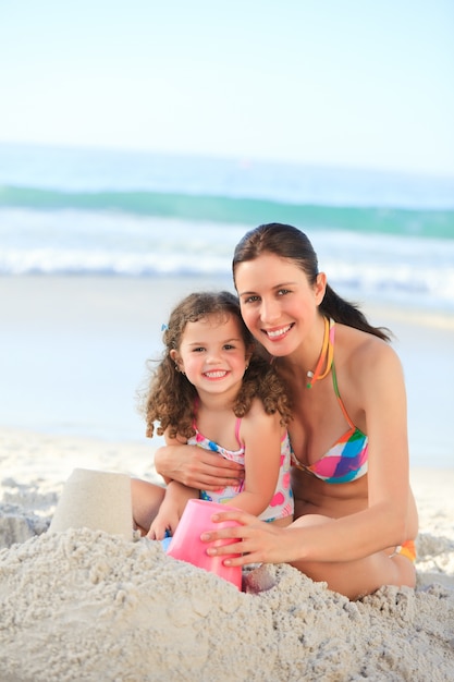 Hija con su madre haciendo un castillo de arena