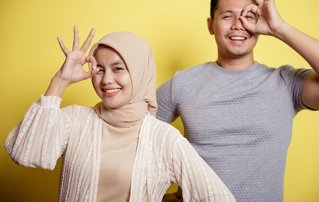 Hijab-Frauen und -Männer glücklich und zeigen zusammen OK-Zeichen. isoliert auf gelbem Hintergrund