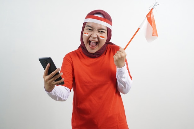 Hijab de mujer feliz con bandera roja y blanca con teléfono inteligente