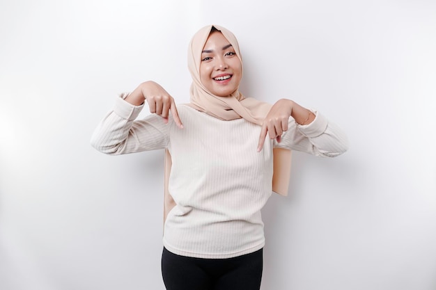 Hijab de mujer musulmana asiática emocionada señalando el espacio de copia debajo de ella aislado por fondo blanco