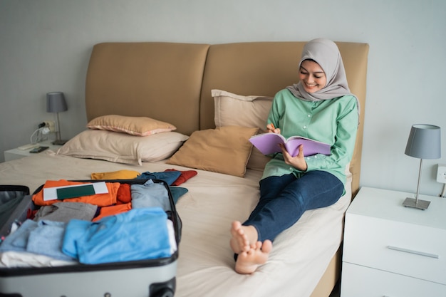 Hijab mujer sentada en la cama mientras mira un cuaderno