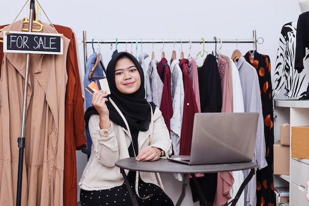 Hijab mujer sosteniendo tarjetas de crédito en la tienda de ropa Servicio de pago con tarjeta de crédito