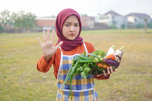 Hijab mujer usar delantal sostener cesta de parada de gesto vegetal