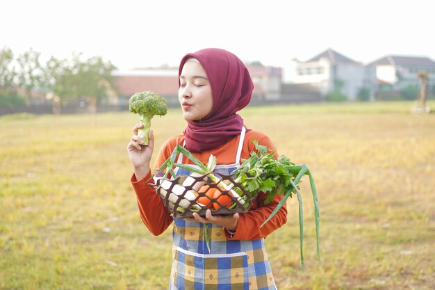 Foto hijab mulher usa avental carregando cesta cheia de legumes