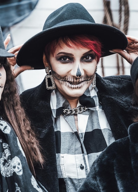 Hijas de madres de familia aterradoras celebrando halloween Aterrador maquillaje de media cara de calavera negra y disfraces de brujas imágenes elegantesHorrorfun at children's party in barn on streetSombreroschaquetas